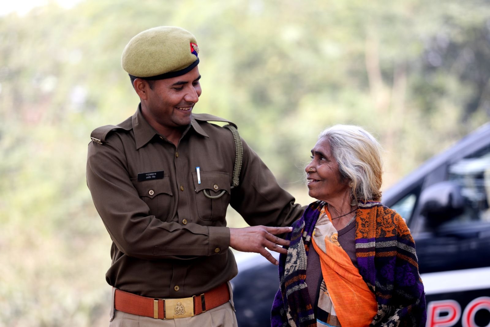 Police adhikari buzurg mahila ki sahayata karte hue — Bhagyank 9 ki raksha-bhavna aur karuna ka pratik
