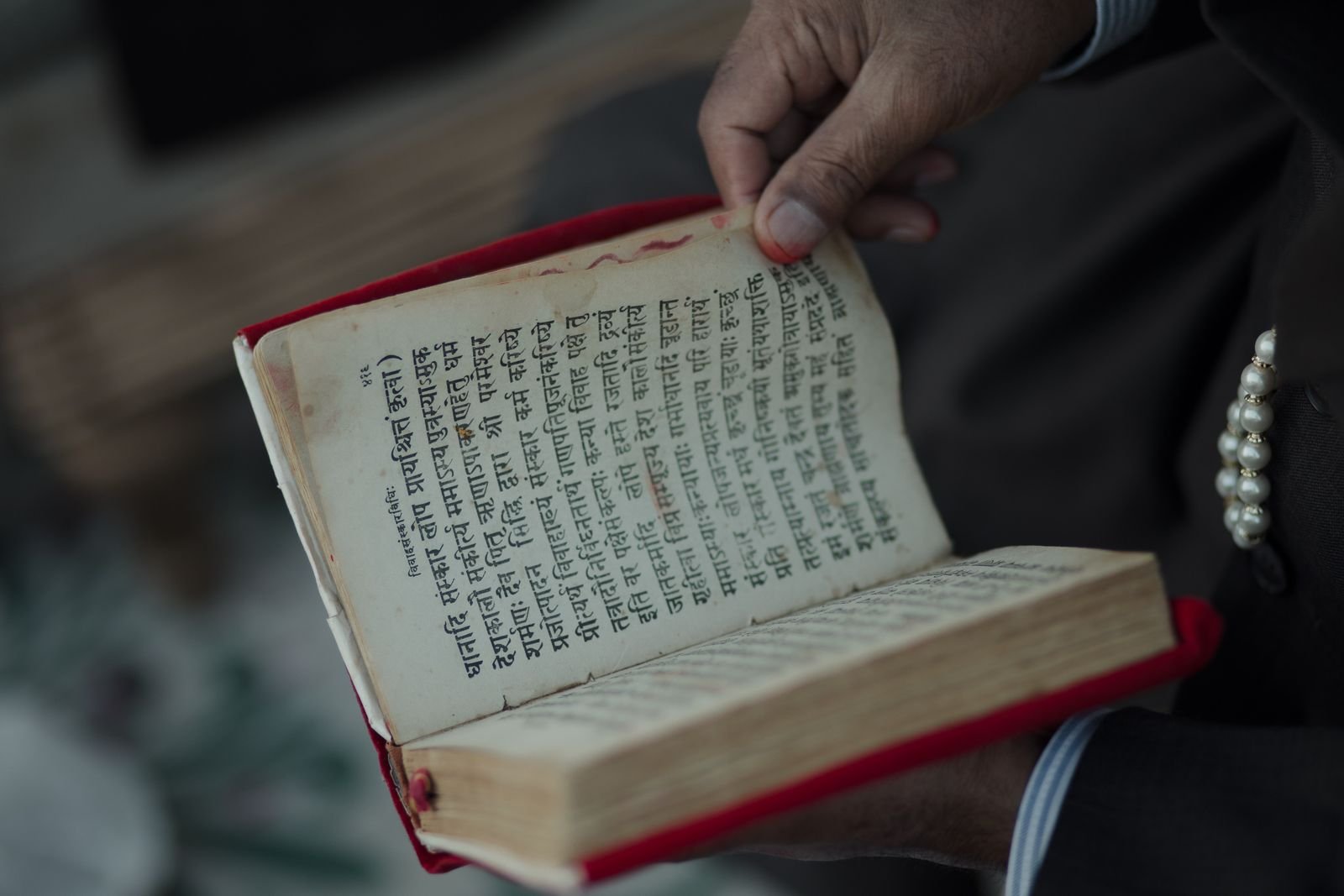 Haath mein prachin Sanskrit likhit pustak — Chaldean numerology ki puratan parampara ka pratik