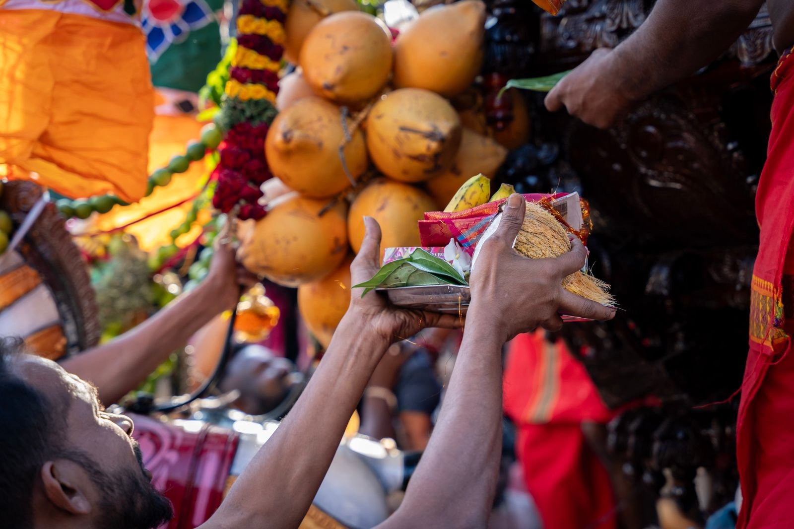 मंदिर में नारियल और पूजा-सामग्री का दान करते हुए हाथ