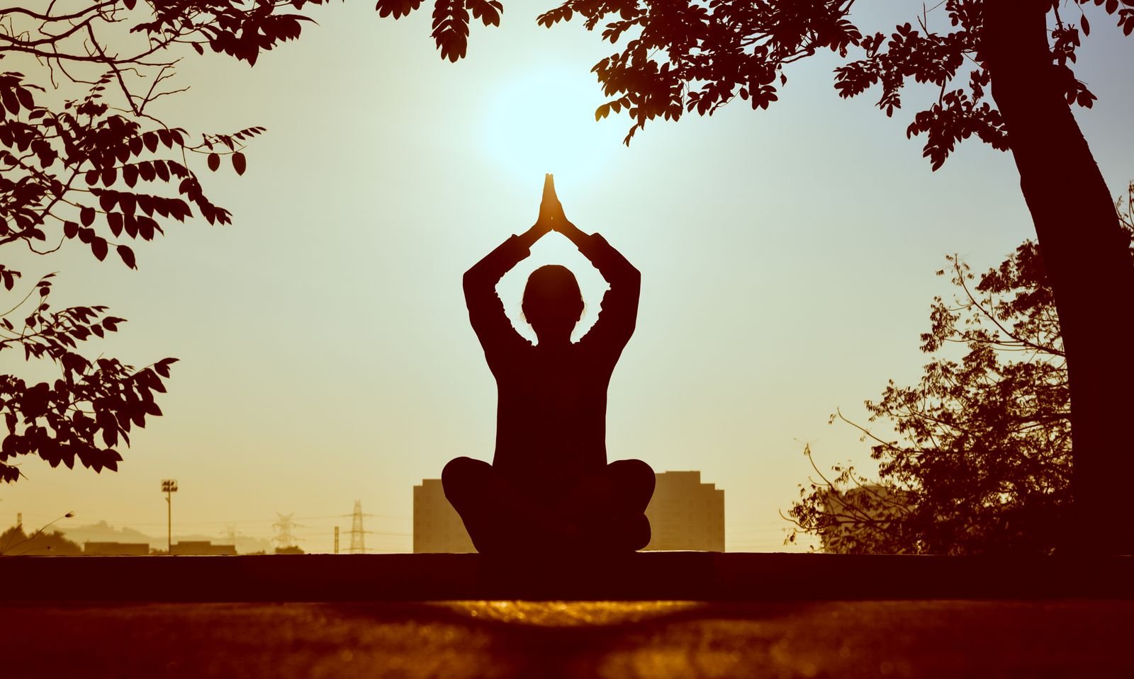 सूर्योदय के समय ध्यान मुद्रा में बैठा व्यक्ति, हाथ सिर के ऊपर जोड़कर, मास्टर नंबर की सहज-ज्ञान शक्ति का प्रतीक