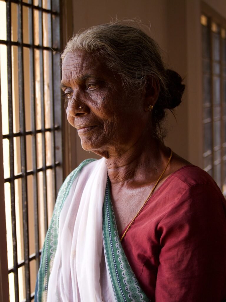 खिड़की से बाहर देखती सोच में डूबी महिला